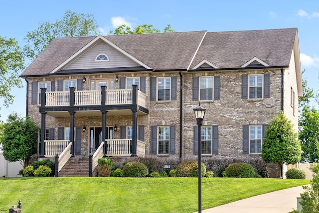 view of front facade featuring a front lawn, a balcony, and covered porch