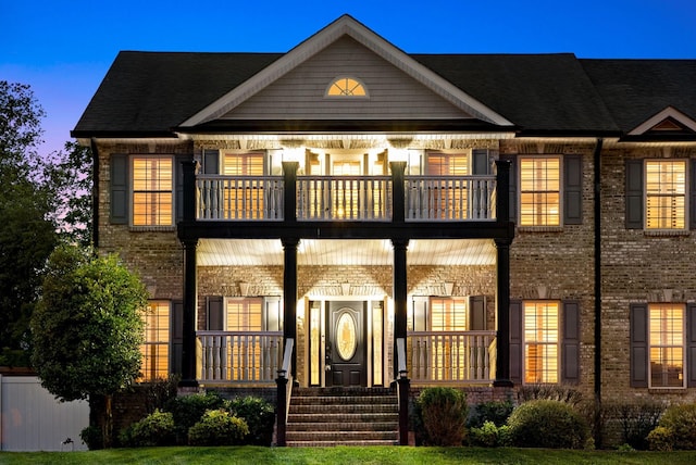 view of front of house featuring a balcony and brick siding