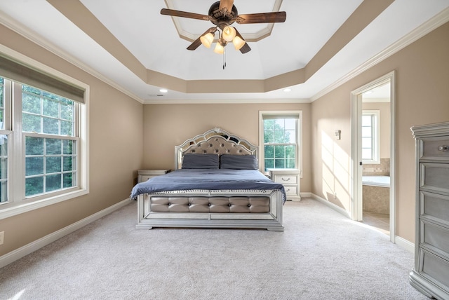 carpeted bedroom with ornamental molding, ceiling fan, ensuite bath, and a tray ceiling