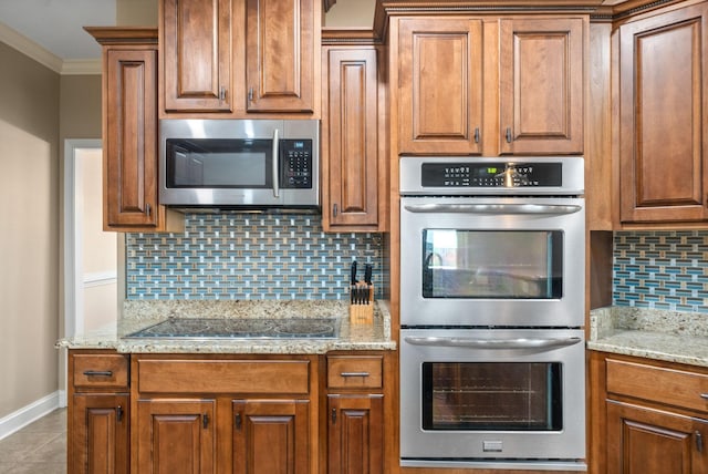 kitchen with appliances with stainless steel finishes, backsplash, light tile patterned floors, crown molding, and light stone countertops