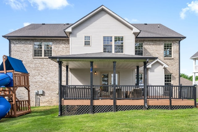 back of house featuring roof with shingles, brick siding, a lawn, and a playground