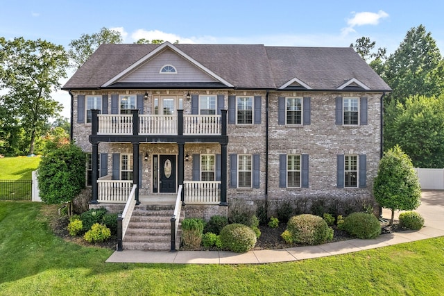 view of front facade with a front lawn, a balcony, and a porch