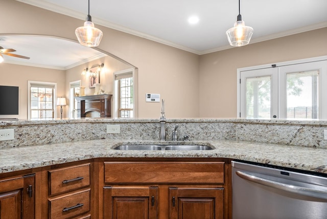 kitchen featuring light stone counters, arched walkways, decorative light fixtures, stainless steel dishwasher, and a sink