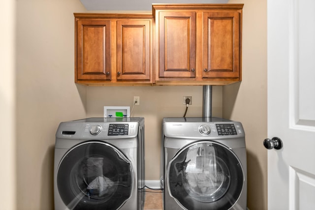 washroom featuring cabinet space, washer and clothes dryer, and baseboards