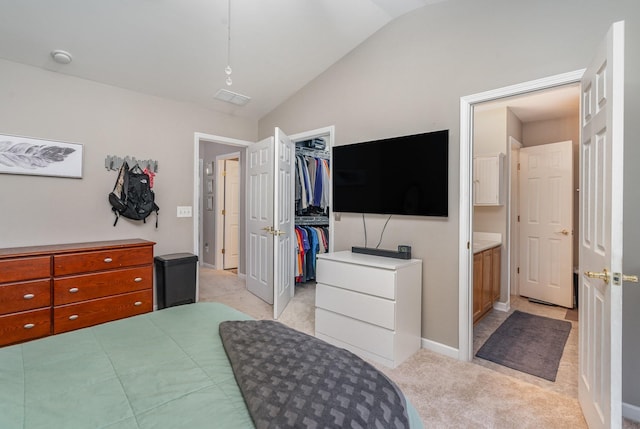 bedroom featuring connected bathroom, light carpet, a spacious closet, vaulted ceiling, and a closet