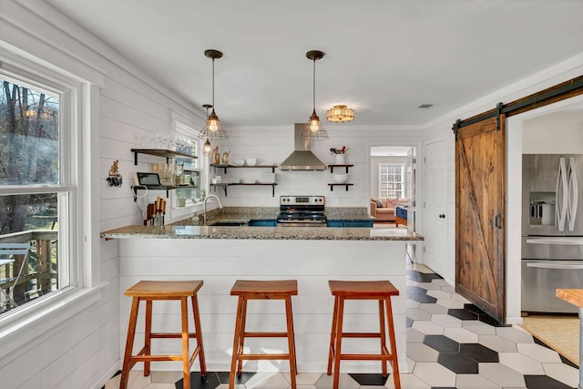 kitchen featuring a kitchen bar, a barn door, kitchen peninsula, and appliances with stainless steel finishes