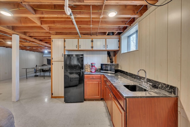 kitchen featuring black fridge, dark stone counters, and sink