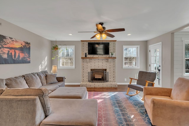 living room with dark wood-type flooring, ceiling fan, and a brick fireplace