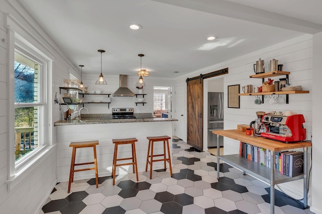 kitchen featuring ventilation hood, a kitchen breakfast bar, kitchen peninsula, stainless steel appliances, and a barn door