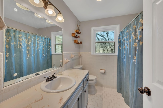 bathroom with tile patterned flooring, vanity, toilet, and tile walls