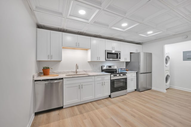 kitchen with sink, stainless steel appliances, white cabinets, and stacked washer and dryer