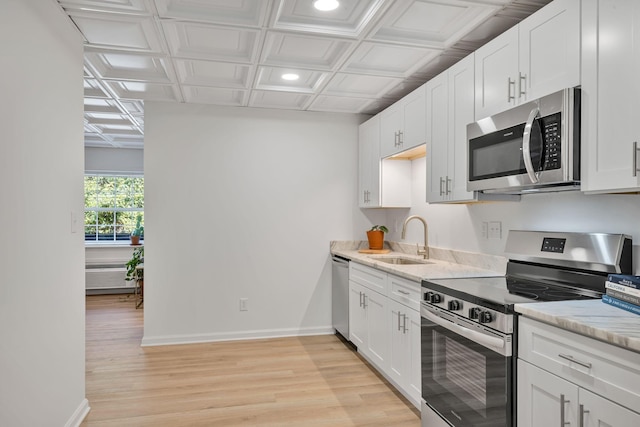 kitchen featuring appliances with stainless steel finishes, light stone countertops, sink, and white cabinets