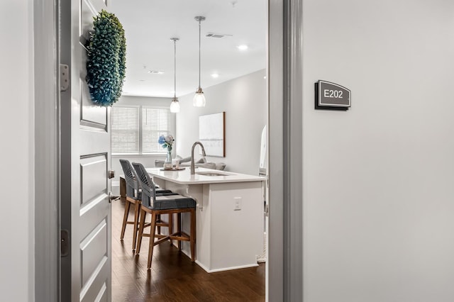 kitchen featuring sink, a kitchen breakfast bar, dark hardwood / wood-style floors, a center island, and decorative light fixtures