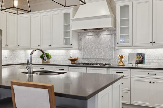 kitchen with premium range hood, sink, an island with sink, and white cabinets