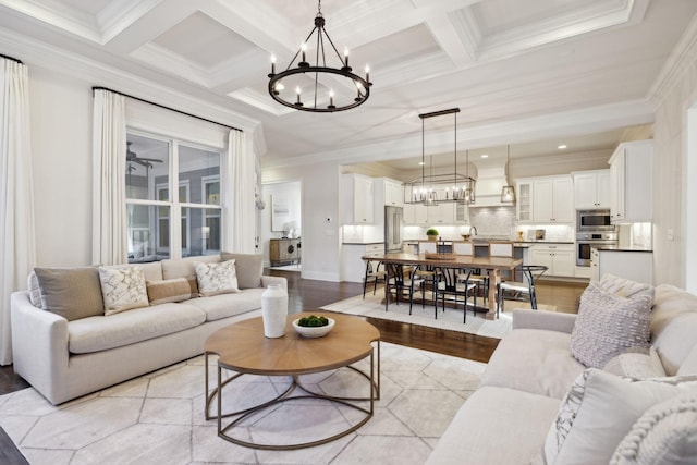 living room with coffered ceiling, crown molding, a chandelier, light wood-type flooring, and beam ceiling