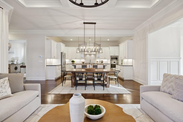 living room featuring crown molding, wood-type flooring, sink, and an inviting chandelier