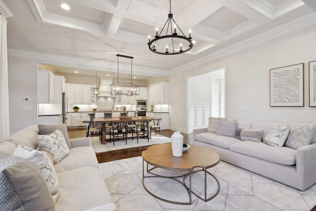 living room featuring beamed ceiling, coffered ceiling, crown molding, and an inviting chandelier