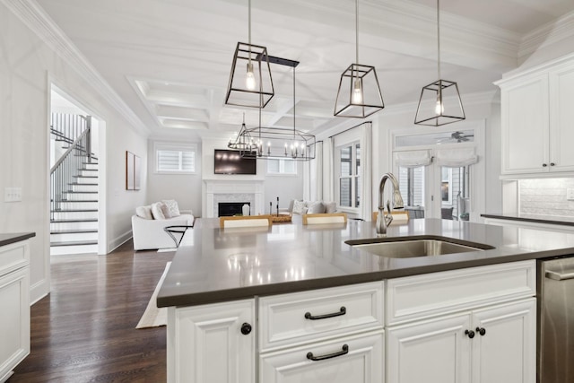 kitchen featuring sink, white cabinetry, hanging light fixtures, dark hardwood / wood-style floors, and an island with sink