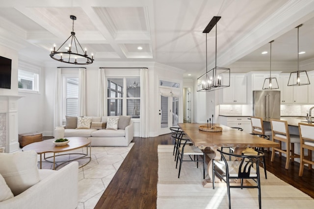 dining area with coffered ceiling, crown molding, a chandelier, light hardwood / wood-style flooring, and beam ceiling