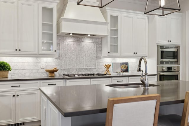 kitchen with sink, white cabinetry, stainless steel appliances, a center island with sink, and custom exhaust hood