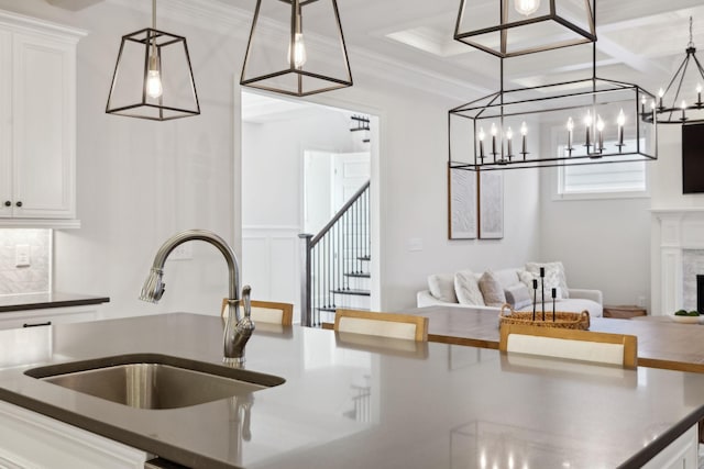 kitchen featuring white cabinetry, coffered ceiling, sink, and a high end fireplace