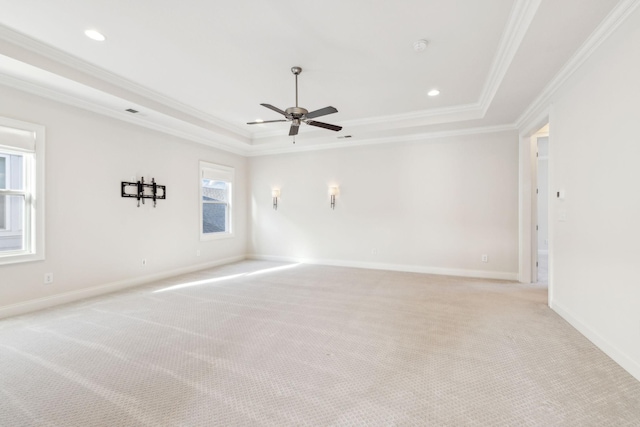 carpeted empty room featuring crown molding, ceiling fan, and a tray ceiling