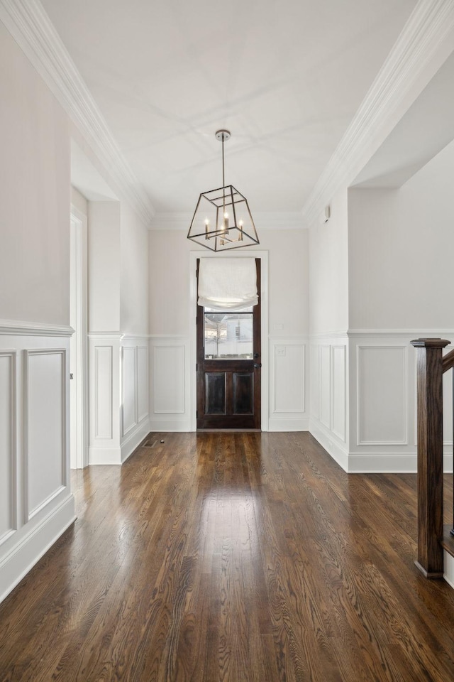 foyer with dark wood-type flooring, ornamental molding, and a chandelier