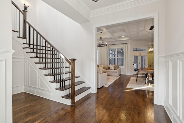 staircase with hardwood / wood-style floors, beamed ceiling, coffered ceiling, a notable chandelier, and crown molding