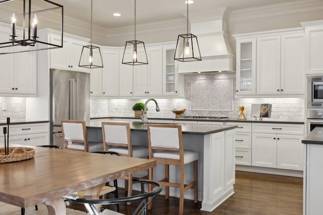 kitchen featuring hanging light fixtures, an island with sink, appliances with stainless steel finishes, and white cabinetry