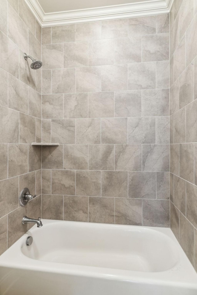 bathroom with ornamental molding and tiled shower / bath