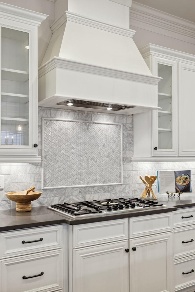 kitchen featuring premium range hood, backsplash, stainless steel gas cooktop, and white cabinets