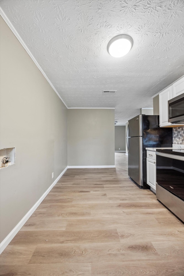 kitchen featuring white cabinetry, stainless steel appliances, light hardwood / wood-style floors, and a textured ceiling