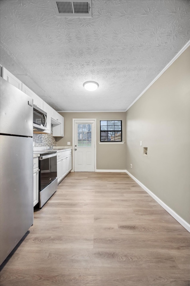 kitchen with tasteful backsplash, white cabinetry, appliances with stainless steel finishes, and light wood-type flooring