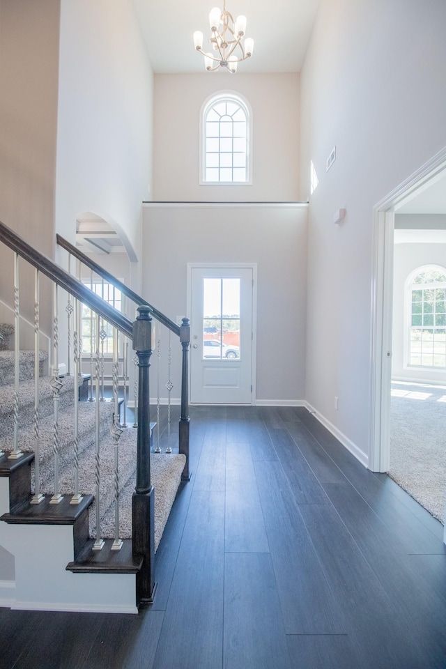 interior space featuring a high ceiling, plenty of natural light, a chandelier, and dark hardwood / wood-style flooring