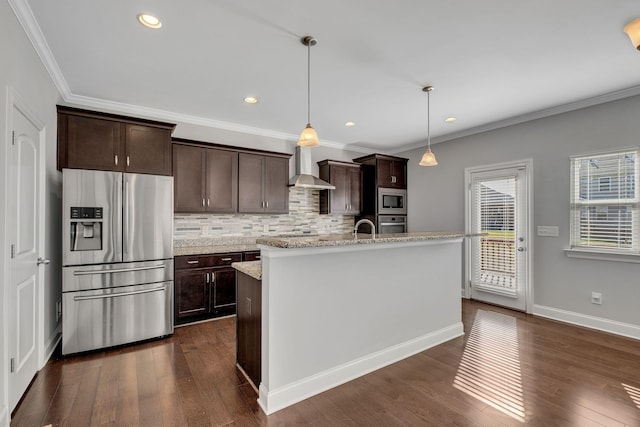 kitchen featuring pendant lighting, an island with sink, stainless steel appliances, dark brown cabinets, and wall chimney exhaust hood