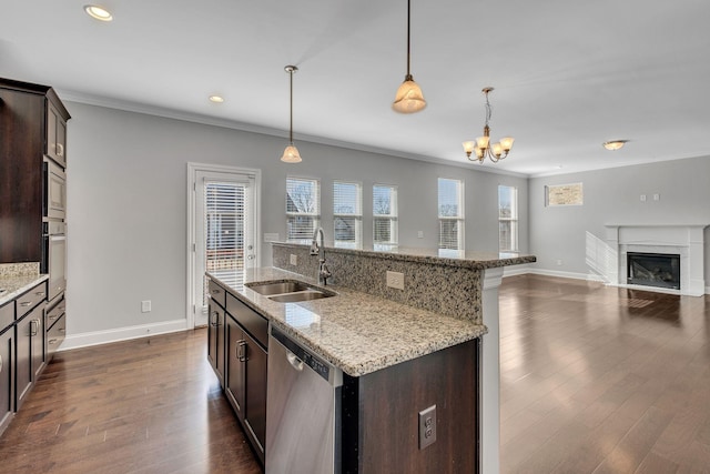 kitchen with dark brown cabinetry, sink, hanging light fixtures, appliances with stainless steel finishes, and an island with sink