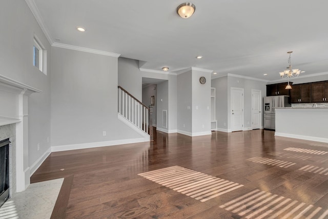 unfurnished living room with dark wood-type flooring, ornamental molding, a fireplace, and a chandelier