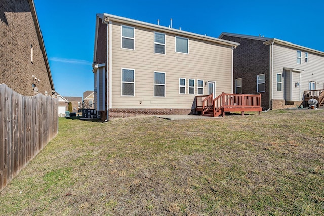 rear view of property featuring a wooden deck and a lawn