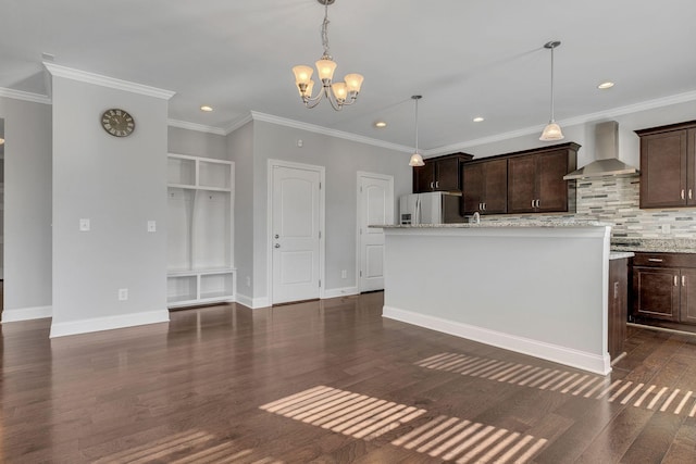 kitchen featuring pendant lighting, dark brown cabinetry, a center island with sink, stainless steel fridge with ice dispenser, and wall chimney exhaust hood