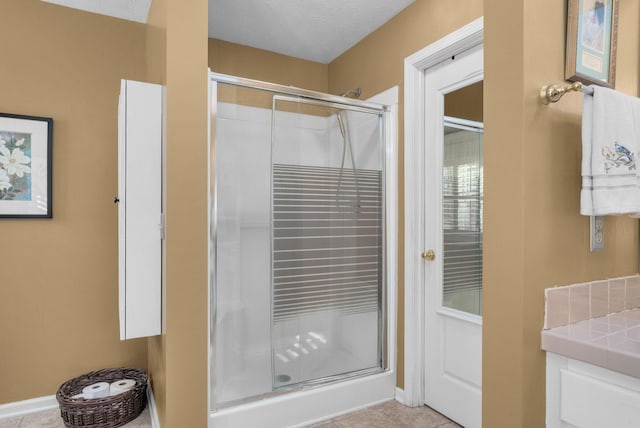 bathroom featuring vanity, a shower with door, and a textured ceiling