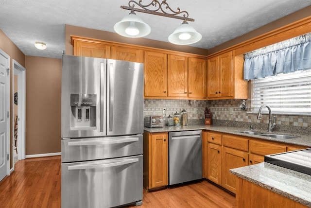 kitchen with decorative light fixtures, tasteful backsplash, sink, stainless steel appliances, and light stone countertops