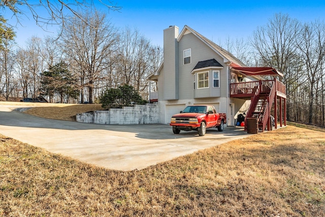 view of side of home with a garage, a lawn, and a deck