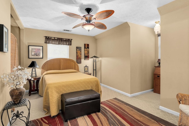 carpeted bedroom featuring ceiling fan and a textured ceiling