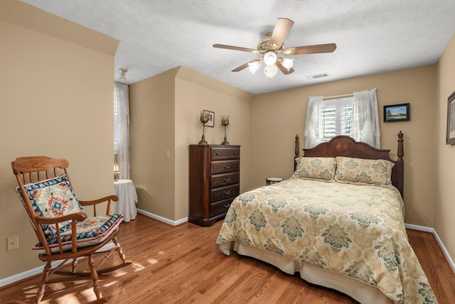 bedroom featuring wood-type flooring, ceiling fan, and a textured ceiling