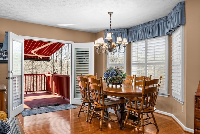 dining room with wood-type flooring, a textured ceiling, and a notable chandelier