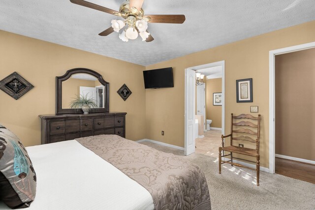 carpeted bedroom featuring ceiling fan, connected bathroom, and a textured ceiling