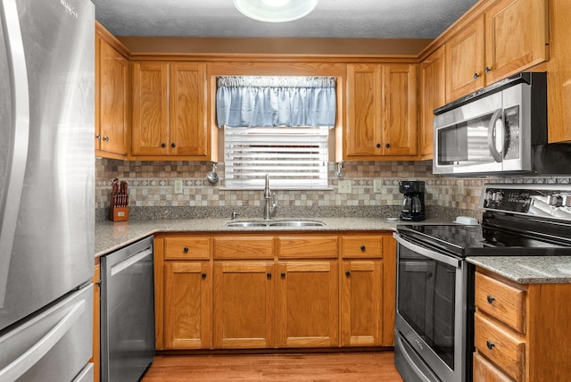 kitchen with tasteful backsplash, stainless steel appliances, light stone countertops, and sink