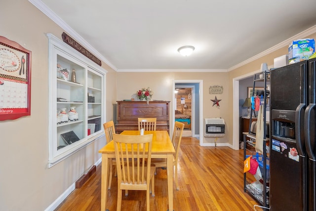 dining room with crown molding, heating unit, and light hardwood / wood-style flooring