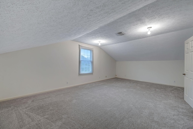 additional living space with vaulted ceiling, carpet, and a textured ceiling