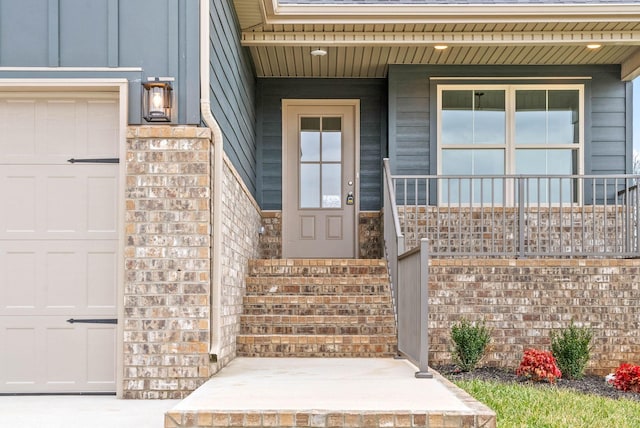 view of exterior entry with a garage, covered porch, and brick siding